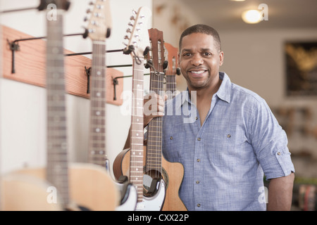 Native American man tenendo la chitarra in music store Foto Stock