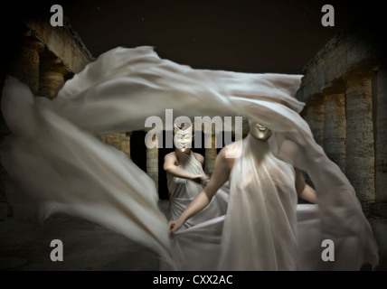 Due ballerini indossano maschere di danza che scorre con un panno bianco in un tempio romano Foto Stock