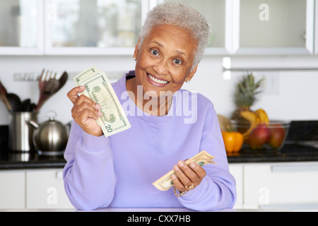 African American donna conteggiare denaro in cucina Foto Stock