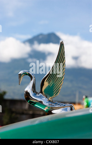 Ornamento del cofano sul bus a Antigua stazione bus dominato da attivo vulcano Fuego. Guatemala, America Centrale Foto Stock