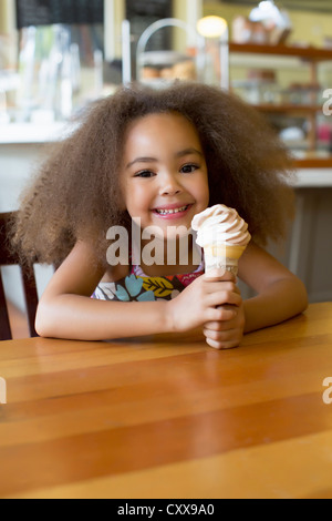 Razza mista ragazza a mangiare il gelato cono Foto Stock
