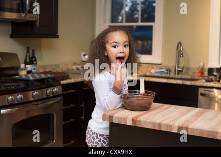 Razza mista ragazza leccare pastella Foto Stock