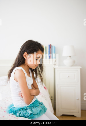 Razza mista ragazza seduta sul letto Foto Stock