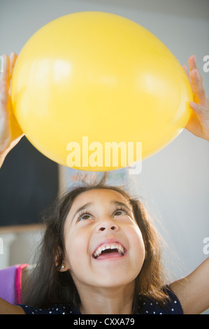 Razza mista ragazza con palloncino giallo Foto Stock