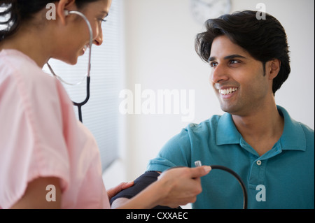 Razza mista infermiera facendo pressione del sangue del paziente Foto Stock