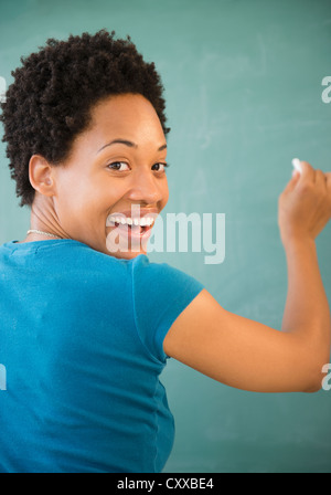 African American donna scrivere sulla lavagna Foto Stock