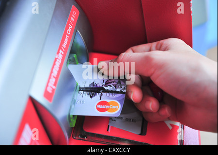 Mano femmina inserisce una tessera in materia plastica nell'ATM Foto Stock