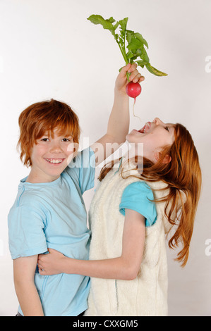 Ragazzo alimentazione di un ravanello di una ragazza Foto Stock