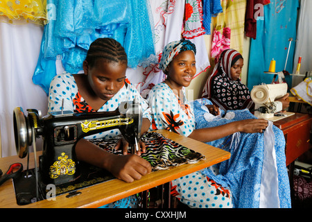 Le donne con le macchine da cucire in un negozio di sartoria a Zanzibar / Tanzania Foto Stock