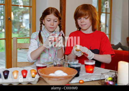 Un ragazzo e una ragazza la colorazione delle uova pasquali, pittura delle uova di Pasqua Foto Stock