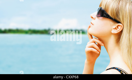 Rilassata giovane donna con occhiali da sole e la visualizzazione di un'isola delle Maldive Foto Stock