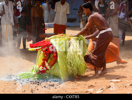 Theyyam Artista rituale con foglie e ceneri di fronte al pubblico, Thalassery, India Foto Stock