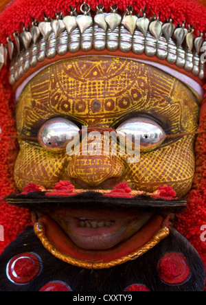 Uomo vestito per cerimonia Theyyam con la pittura tradizionale sul suo viso e maschera sugli occhi Thalassery, India Foto Stock