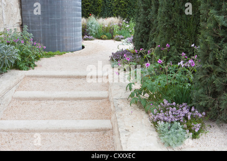 Moderno e contemporaneo giardino di ghiaia con gradini in pietra e bordi di fiori e erbe ornamentali Chelsea RHS fiore mostra giardini Londra UK Foto Stock