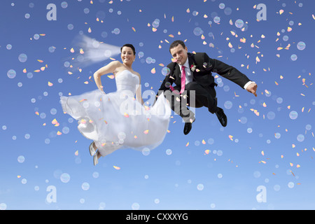 Sposa e lo sposo, coppia di sposi il salto in aria, contro un cielo blu, bolle, coriandoli Foto Stock