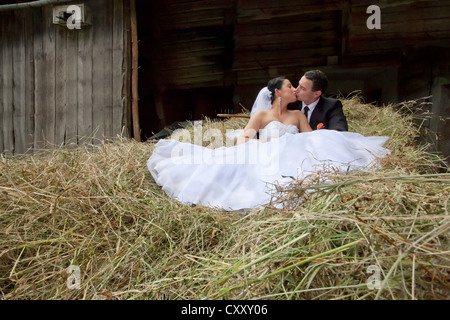 Sposa e lo sposo, sposi seduti sul fieno fieno sparso, granaio Foto Stock