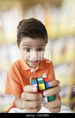 Sorpreso in cerca ragazzo con una magia cubo Foto Stock