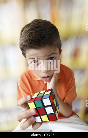 Confuso in cerca ragazzo con una magia cubo Foto Stock