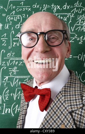 Maestro sorridendo, professore, davanti alla scuola di blackboard con formule matematiche, classe di matematica Foto Stock