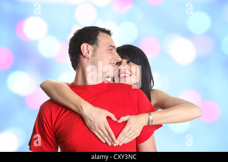 Coppia giovane abbracciando e formando una a forma di cuore gesti con le mani Foto Stock