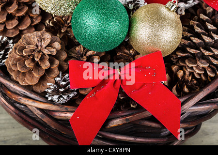 Cesto pieno di pigne, ornamenti e nastri per la stagione di natale Foto Stock