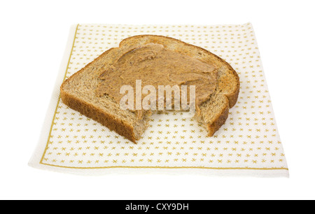 Un pezzo di grano tostato con burro di mandorla che è stato picchiato una volta su un tovagliolo di carta. Foto Stock