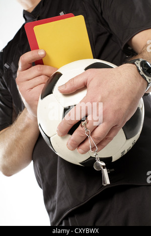 Arbitro tenendo un calcio e rosso e cartellini gialli Foto Stock