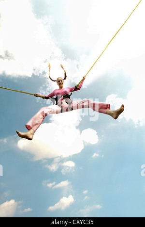 Giovane donna salta con le corde di un bungee trampolino Foto Stock