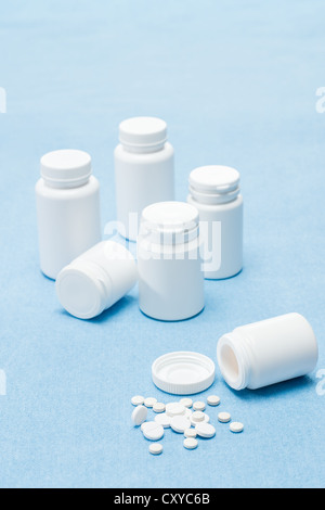 Medicamento pillole compresse spillato dal flacone medici su sfondo blu Foto Stock