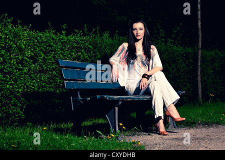 Giovane donna seduta su una panchina Foto Stock