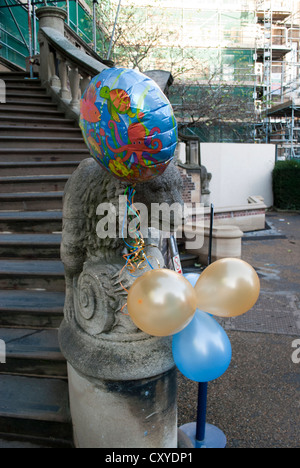 Palloncini legato su di una statua di pietra di un cane sui gradini all'ingresso del ponteggio Museo di Scienze della Terra Foto Stock