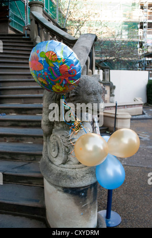 Palloncini legato su di una statua di pietra di un cane sui gradini all'ingresso del ponteggio Museo di Scienze della Terra Foto Stock