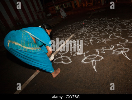 Donna in Sari piegato verso il basso Kolam disegno per una cerimonia in strada, Trichy, India Foto Stock