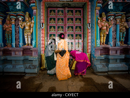 Tre donne In Sari mettendo offre nella parte anteriore del portale decorato di Sri Ranganathaswamy tempio, Trichy, India Foto Stock