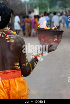 Vista posteriore di un uomo con la pittura sul suo corpo tenendo un vaso sul fuoco in una mano camminare sul fuoco rituale, Madurai, in India del Sud Foto Stock