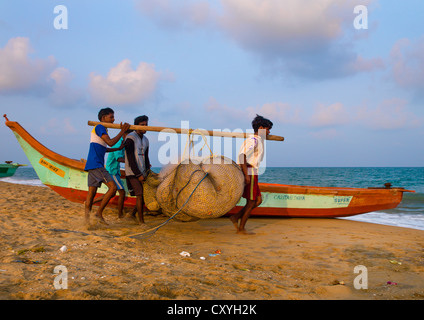 I pescatori usando un bastone di legno per trasportare le loro reti sulla spiaggia di Mahabalipuram, India Foto Stock