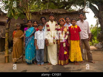 Giovane sposa e lo Sposo vestito per cerimonia e ornata con ghirlande di fiori in posa circondato da famiglia, Pondicherry, India Foto Stock