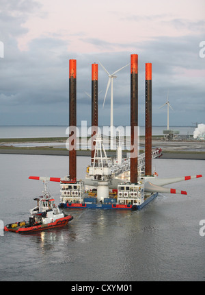 Nave utilizzata per la costruzione di parchi eolici offshore lascia Eemshaven portante una testa di turbina eolica, guidato da barche rimorchiatore. Foto Stock