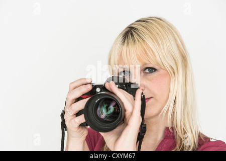 Giovane donna tenendo una fotocamera reflex Foto Stock