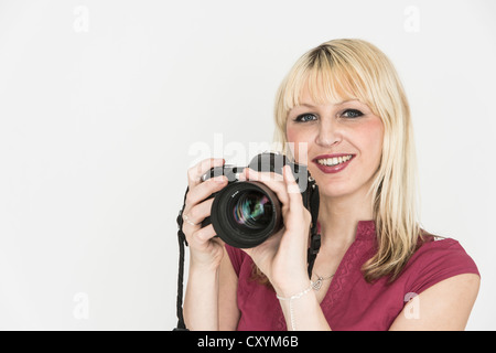 Giovane donna tenendo una fotocamera reflex Foto Stock