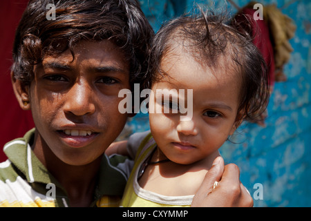 Ragazzo con la bambina sulle braccia in Kolkata, India Foto Stock