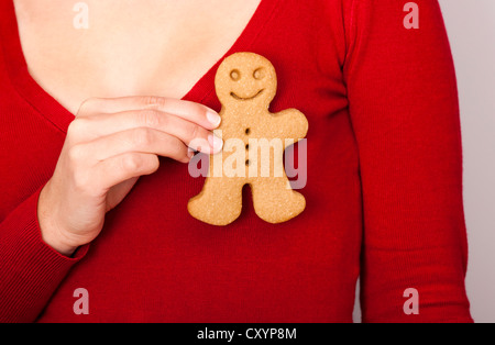 Femmina lato tenendo un gingerbread cookie vicino al suo cuore Foto Stock