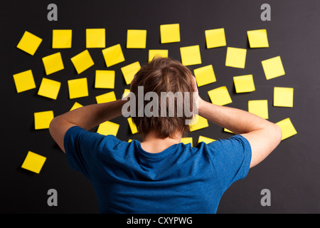 Giovane studente con stress e cercando di una pensione completa di note di colore giallo Foto Stock