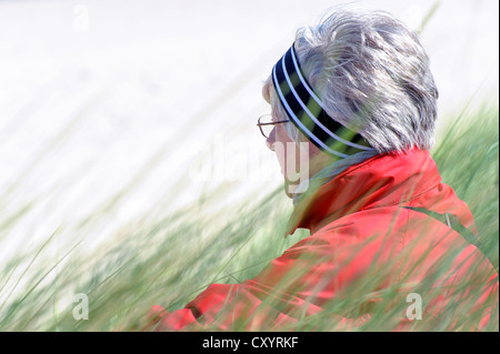 Donna seduta tra l'erba marram sulle dune della Costa Baltica, Meclemburgo-Pomerania Occidentale Foto Stock