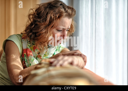 Giovane donna con la faccia triste seduto su un divano Foto Stock