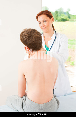 Chirurgo ortopedico esaminando un ragazzo adolescente il collo Foto Stock