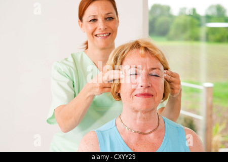 Paziente che viene massaggiato sulla sua templi da un fisioterapista Foto Stock