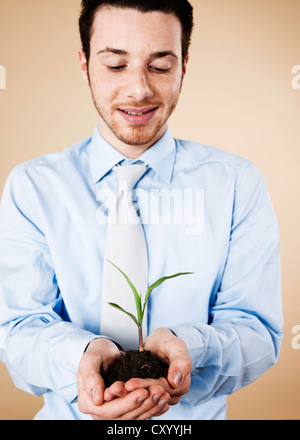Sorridente giovane manager tenendo un impianto nelle sue mani Foto Stock