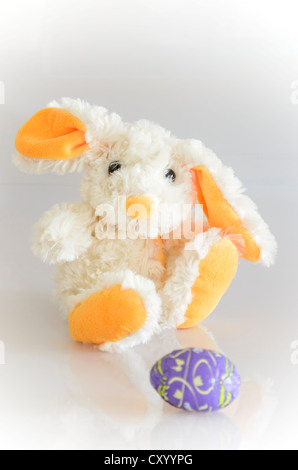 Peluche, bunny, con un viola uovo di cioccolato Foto Stock