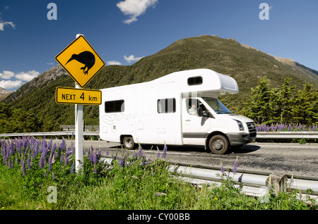 Caravan passato di guida un cartello di avvertimento su una autostrada, 'Kiwi avanti 4 km', facchini Pass, gamma Craigieburn, Canterbury, Isola del Sud Foto Stock